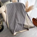 Dettaglio del motivo jacquard geometrico su una morbida sciarpa invernale con bordo a frange - 180cm / Grigio