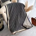 Scialle in maglia a motivi geometrici nero e beige con frange su un divano - 180cm / Nero