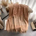 Beige ethnic shawl with intricate floral embroidery and tassel fringe on a sofa - Khaki