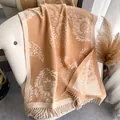 Primer plano del patrón jacquard floral vintage y flecos de un cálido chal tejido - 180cm / Caqui