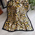 Elegante sjaal van imitatiezijde met luipaardprint en zwarte rand op houten vloer - Geel