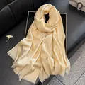 Detail of champagne gold silk scarf with jacquard pattern and tassel edges on a black tray - Apricot