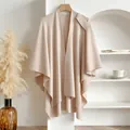 Elegant beige knitted cape shawl with a side decorative strap hanging on a wooden hanger - Apricot