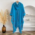 Blue knitted hooded poncho with colorful stripes and fringe hem on a wooden hanger - Blue