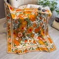 Élégant foulard en soie de 90 cm à fleurs orange avec bordure camel sur un canapé - Orange