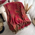 Scialle rosso con motivo paisley e frange eleganti su un divano beige - Rosso