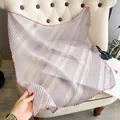 Elegant pleated light gray silk scarf with pink edges displayed on a sofa - Large Square / Gray