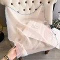Light pink pleated silk scarf with blue edges displayed on a sofa for casual elegance - Large Square / Pink