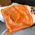 Elegant orange paisley silk-feel square scarf styled with a brown luxury handbag - Orange