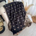 Black cashmere shawl with golden heart patterns and fringe tassels on an armchair - Black