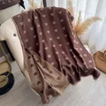 Dark brown heart patterned shawl with gold foil print and fringe edges on sofa - Brown