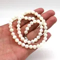 Polished natural white mother of pearl round beads held by hand for jewelry DIY - 2mm / White