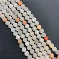 Primer plano de cuentas de piedra natural pulida en tonos crema, melocotón y naranja - Talla 6