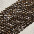 Cuentas redondas de piedra natural marrón oscuro sobre fondo de tela beige texturizada - Gris Bronce