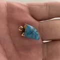 Triangle turquoise stone pendant with gold-plated edge held in hand for scale - 10x20mm / Blue Turquoise