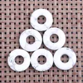 Macro-opname van zes witte marmeren donut hangers op een bruine geweven textuur mat - Howliet