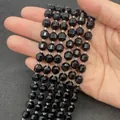Faceted black natural stone beads for DIY jewelry making held in hand for scale - Black Agate