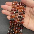 Faceted red carnelian agate beads string held in hand showing natural stone texture - Red Agate