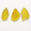Primo piano di tre ciondoli a fette di agata gialla irregolari con texture naturali per DIY - Giallo