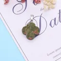 Dettaglio del ciondolo a quadrifoglio in unakite con gancio in metallo argentato - Unakite