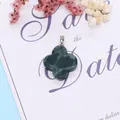 Green aventurine four-leaf flower pendant with silver clasp on decorative background - Rhyolite