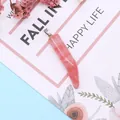 Detail of pink natural stone horn pendant with silver bail on a floral display card - 8x42mm / Watermelon Quartz