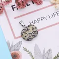 Close-up of apple-shaped Dalmatian Jasper stone pendant with silver metal bail on floral card - Dalmatian Jasper