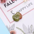 Natural heart-shaped unakite gemstone pendant with silver metal clasp on floral background - Unakite