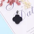 Polished black four-leaf clover pendant with silver edges on a decorative card - Black Agate