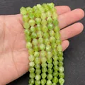 Strands of faceted olive green natural stone beads held in hand for DIY jewelry making - Peridot