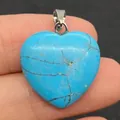 Blauwe turquoise hartvormige hanger met zilveren sluiting vastgehouden door vingers - Blauw Turkoois