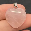 Hartvormige rozenkwarts hanger met zilveren oogje in de hand getoond voor de maat - Rozenkwarts