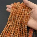 Faceted orange natural agate stone beads held against a black textured background - No. 25 / 6mm