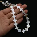Vue détaillée de perles en nacre naturelle en forme de croix pour la création de bijoux - Croix