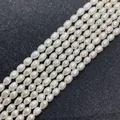 Macro shot of natural rice-shaped white freshwater pearls on textured black background - 3-4mm / White