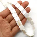 Strang schillernder quadratischer Naturmuschelperlen in der Hand für DIY-Schmuckkreationen - Quadratisch