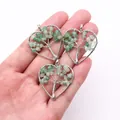 Detailed view of handmade silver wire heart pendants with green natural stones on hand - Green Aventurine