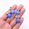 Makro-Detail von blauen katzenaugenförmigen Apfelanhängern mit silbernen Metallösen - Blauer Katzenaugenstein