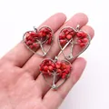 Handheld view of tree of life heart pendants crafted with red natural stone and silver wire - Sea Pearl Coral