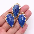 Gros plan de pendentifs flèches en lapis-lazuli avec bordures dorées sur main - Lapis-lazuli