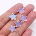 Close-up of five-pointed star opal pendants with iridescent finish held in hand - Opal