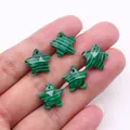 Macro view of five pointed star shaped malachite pendants held to show mini size - Malachite
