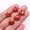Macro shot of five star-shaped red jasper faceted stone pendants held in hand for DIY jewelry - Rainbow Stone