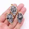 Colgante de flecha de piedra natural gris con borde dorado sostenido para ver el tamaño - Espectrolita Negra