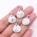 Set of four teardrop white turquoise pendants with natural grey marbling held by hand - 16x17mm / Howlite
