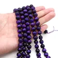 Detailansicht polierter violetter Tigerauge-Perlen mit Katzenaugeneffekt auf der Hand - 4mm Stil (10g) / Lila