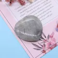 Polierter herzförmiger Labradorit-Naturstein auf dekorativer Blumenkarte im Detail - Blitzstein (Labradorit)