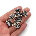 Close-up of hand holding seven natural cowrie shells with black and white polka dot pattern - Style 8 (Black with White Dots)