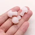 Macro detail of three polished rose quartz mushroom figurines held in a palm for size scale - Rose Quartz