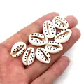 Close-up of handmade white cowrie shells with black polka dots held in palm for DIY jewelry - Style 7 (White with Black Dots)